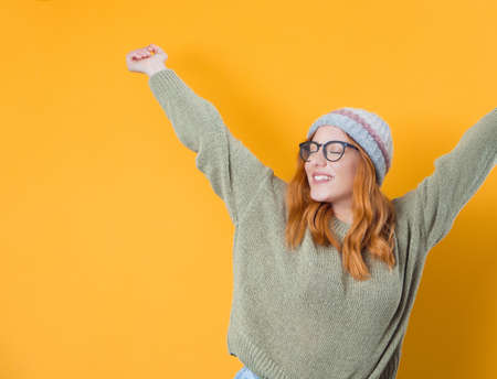 Excited young woman with stretched arms, isolated on yellow background. Pleased girl. Studio shot