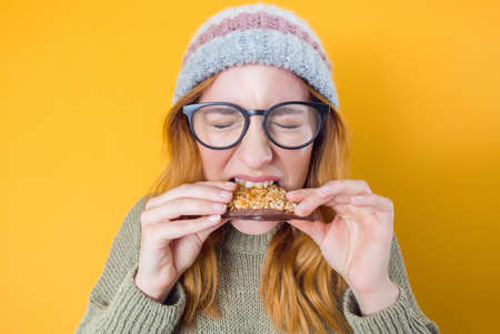 Hungry young woman eating cookies. Student girl holding sweet food, delicious snack, isolated on...
