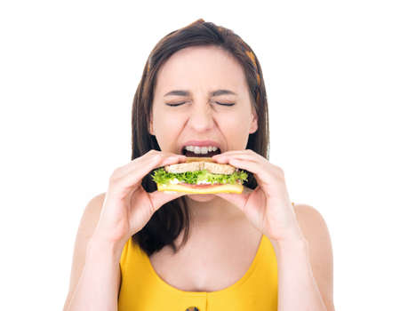 Hungry young woman eating sandwich. Student girl holding fast food, delicious snack, isolated on...