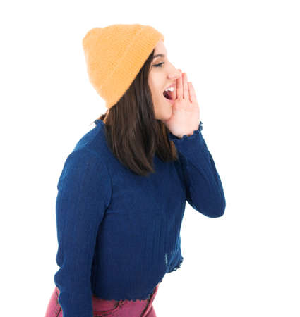 Young woman yelling, isolated on white background. Side view of beautiful girl while says something. Studio shotの写真素材