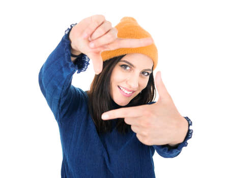 Woman shows frame with her fingers. Young girl set up definition, isolated on white background. Focus on face. Studio shotの写真素材