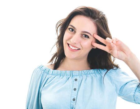 Playful cheerful girl shows peace sing with fingers, isolated on white background. Joyous laughing...