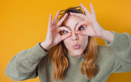 Silly young trendy girl, isolated on yellow background. Funny woman. Joke concept. Studio shotの写真素材