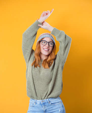 Carefree young woman with raised arms up, isolated on yellow background. Studio shotの写真素材