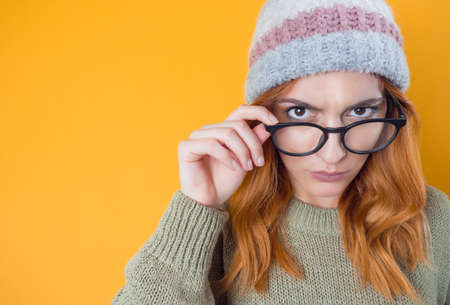 Closeup strict young woman, isolated on yellow background. Jealous pretty girl. Studio shotの写真素材