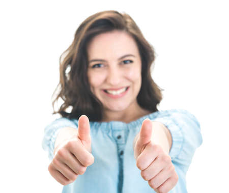 Happy woman with thumbs up, like concept. Isolated on white background. Focus on fingers. Yes gesturing, sings of good work. Studio shotの写真素材