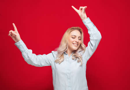 Hands up woman celebrating with stretched arms, isolated on red background. Carefree girl. Studio shotの写真素材