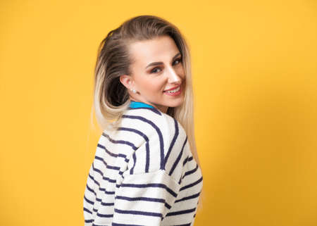 Amusing woman winking and posing, isolated on yellow background. Playful beautiful girl. Studio shot