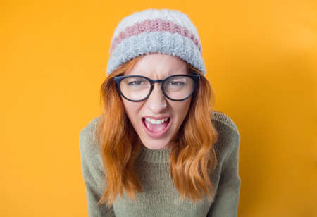 Rage woman looking at camera and screaming, isolated on yellow background. Frustrated female person. Studio shotの写真素材