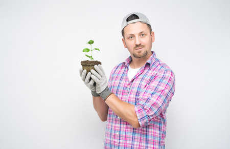 Portrait of male gardener with plant in soil. Plant care concept, isolated on white background. Male farmer. Studio shotの写真素材