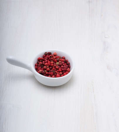 red peppercorn spice in bow on old wooden tableの写真素材