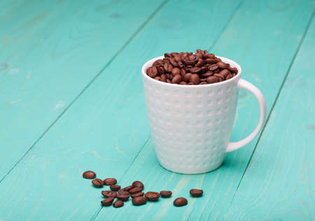 beautiful white coffee cup with coffee beans on wooden background