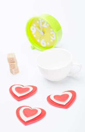 beautiful white cup, sugar, hearts with an alarm clock on a white background