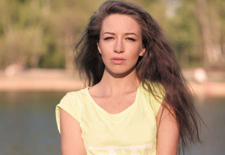 Beautiful Fitness the model in a Top Costs on the bank of the Lake in the Summer on a sunset. Blowing Long Hairの写真素材
