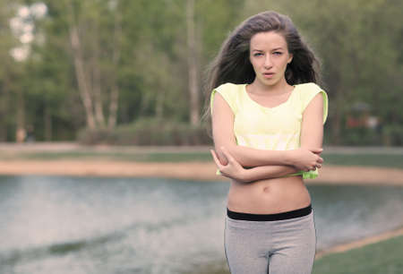 Beautiful Fitness the model in a Top Costs on the bank of the Lake in the Summer on a sunset. Blowing Long Hair.Toned in warm colors.の写真素材