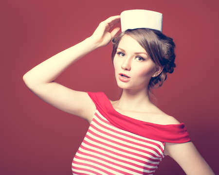 Beautiful pin-up girl dressed a sailor posing on red backgroundの写真素材