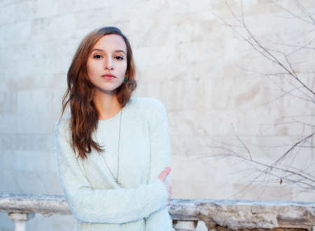 Sunny winter portrait of a beautiful girl in a jacket with a fashionable bagの写真素材