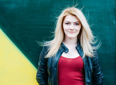 Portrait of a beautiful young blonde woman near green wall. Blowing Long Hair.の写真素材