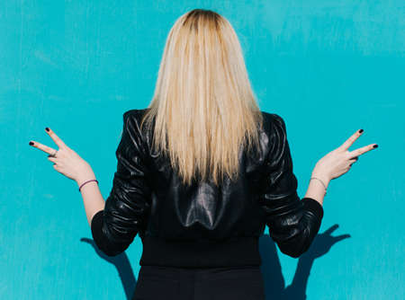Portrait of a young beautiful blonde girl in huge sunglasses on the background of turquoise wall sunny summer dayの写真素材