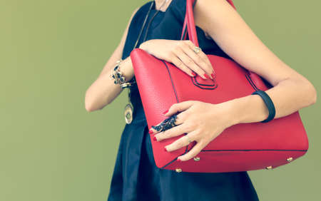 Fashionable beautiful big red handbag on a shoulder of the girl in a black dress trendy. Warm colorsの写真素材