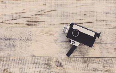 Classic vintage old 8mm movie camera on old wooden boards. Hipster style