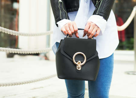 Fashion and Beauty. The girl is holding a fashionable small handbag in hand. Close-up, street-style. Part of the body.の写真素材