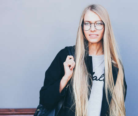 Closeup portrait of blonde girl with long haircut. Hipster, insagram style. She wears black trendy...