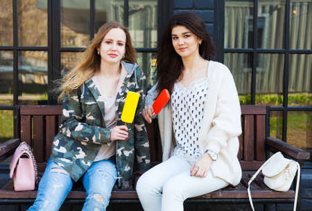 Two girls girlfriends dressed in fashion outfits rest, eat ice cream. Eskimo.の写真素材