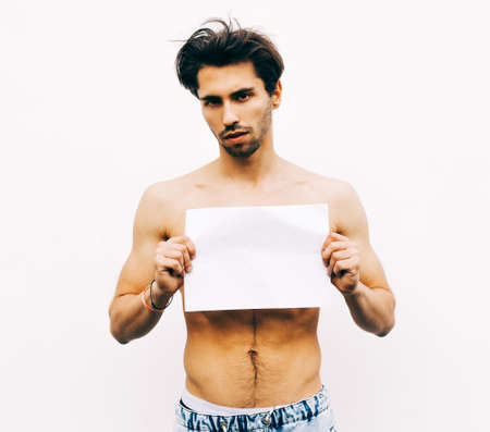 Picture of young man with naked torso holding white blank board