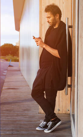 A man in a fashionable black outfit posing at the sunset of a warm summer day in trainers. Streetstyle.の写真素材