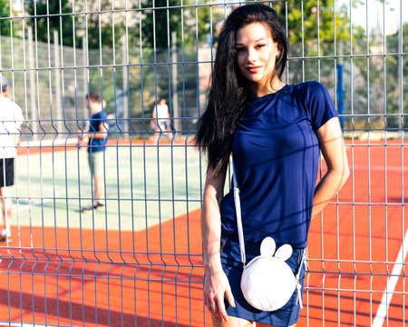 Beautiful tall brunette girl in a short blue dress walking in the park. Street style.