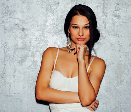 Portrait of brunette sexy young woman in white dress over grey backgroundの写真素材
