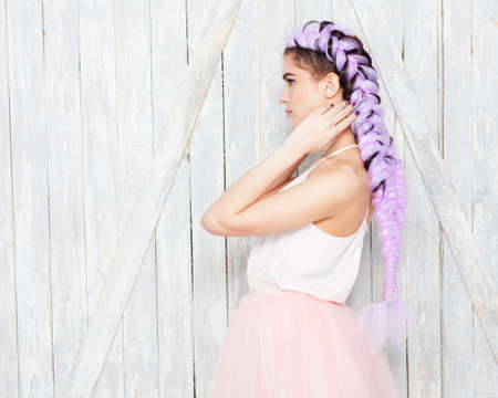 Hairstyle with colored, purple braids. Portrait young cute girl standing in profile showing braids,...
