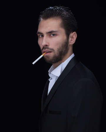 A fashion model in suit and tie enjoying his cigar on black backgroundの写真素材