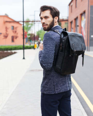 Cheerful young businessman with backpack enjoying walk the cityの写真素材