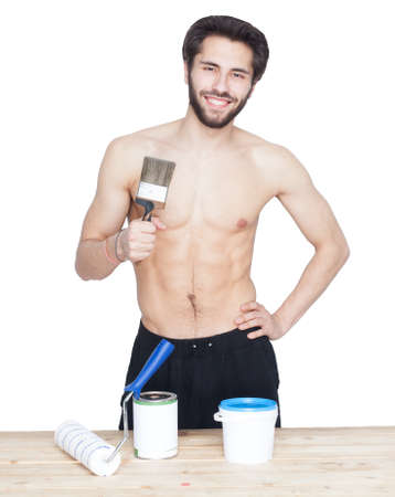 Young shirtless man painter in the workplace. The paint, holding the brush in his hand. Isolation.の写真素材