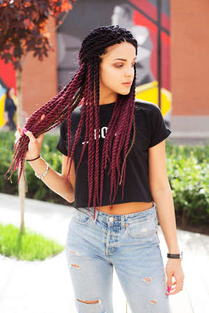 Portrait in the street. Fashionable beautiful girl blogger with braids posing in art space in blue...
