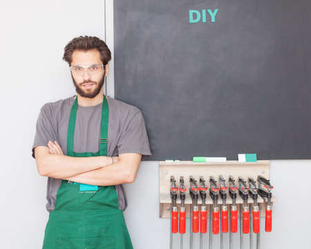 The carpenter's master with a beard in work clothes in a carpentry shop is at the graphite board