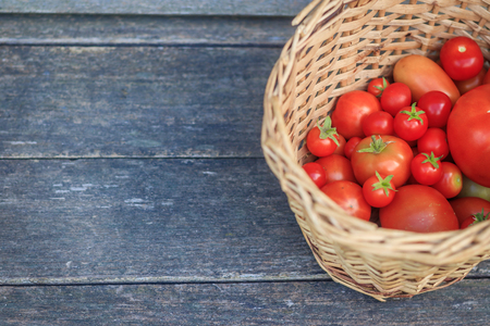 Tomatoes in a basket on a wooden background. Autumn harvest. Harvesting in summer and autumn. Homemade vegetables. Red vegetables.の写真素材