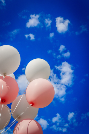 White pink balloons against the sky. Sunny weather and sky with cloudsの写真素材