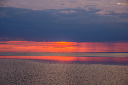A bright sunset on the Gulf of Finland. Sunset at the sea. Sunset on the Gulf. warm summer, crimson sky and small wavesの写真素材