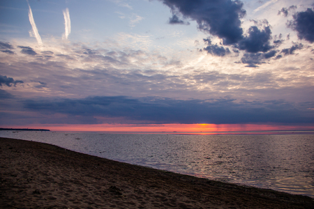 A bright sunset on the Gulf of Finland. Sunset at the sea. Sunset on the Gulf. warm summer, crimson sky and small wavesの写真素材