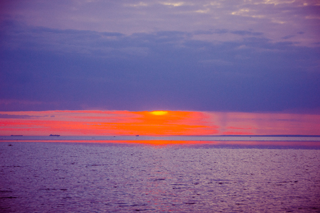 A bright sunset on the Gulf of Finland. Sunset at the sea. Sunset on the Gulf. warm summer, crimson sky and small wavesの写真素材