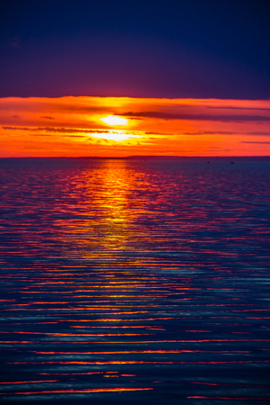 A bright sunset on the Gulf of Finland. Sunset at the sea. Sunset on the Gulf. warm summer, crimson sky and small wavesの写真素材