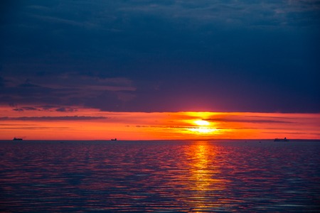A bright sunset on the Gulf of Finland. Sunset at the sea. Sunset on the Gulf. warm summer, crimson sky and small wavesの写真素材