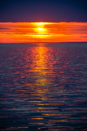 A bright sunset at the sea. Crimson sky and small wavesの写真素材