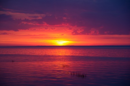 A bright sunset on the Gulf of Finland. Sunset at the sea. Sunset on the Gulf. warm summer, crimson sky and small wavesの写真素材