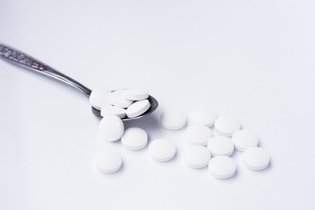 White pills on a white background. A cure for pain. Health and medicine. Chemical elements.