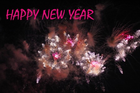 Fireworks on the black sky. Festive show. Large-scale celebration. The explosion of a million lights in the sky. Text Happy New Year on firework backgroundの写真素材