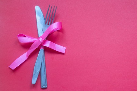 Spoon with a fork tied with a ribbon on a pinkの写真素材